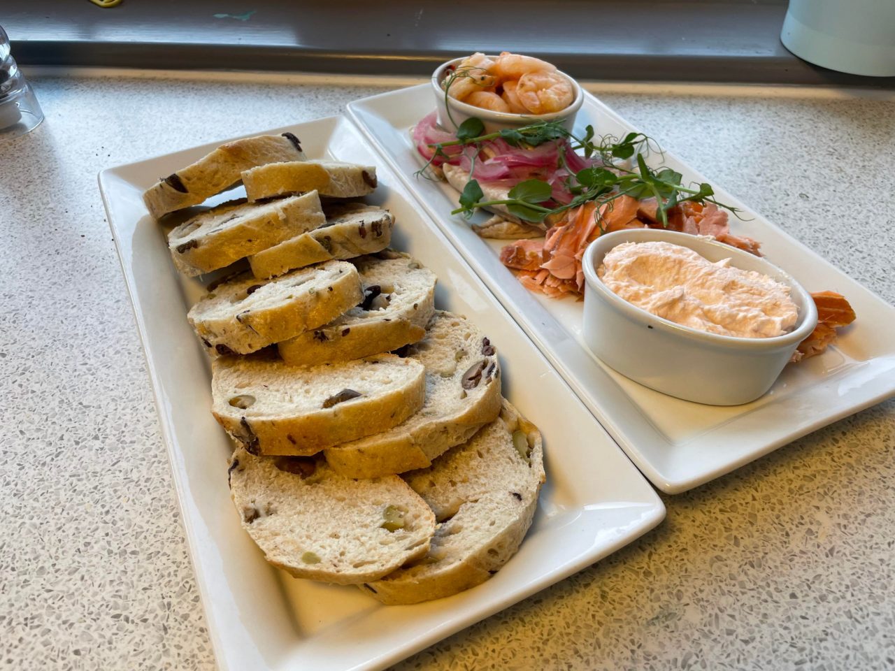 2 plates, 1 with bread, the other with seafood. Ready to eat and share.